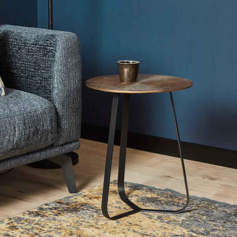 De Salontafel 40 x 50 CM Vierkant staat naast een grijze bank op een houten vloer tegen een blauwe muur. Een enkele donkere beker rust op de tafel, met een deel van een tapijt met patroon zichtbaar in de buurt.