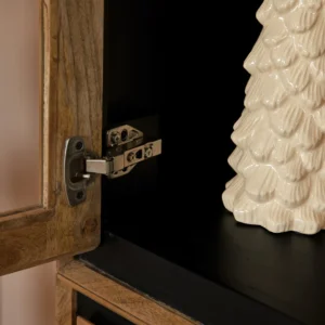Detailopname van een openstaande Richwood vitrinekast met een zilverkleurig scharnier en een decoratieve witte keramische kerstboom op een zwarte plank.