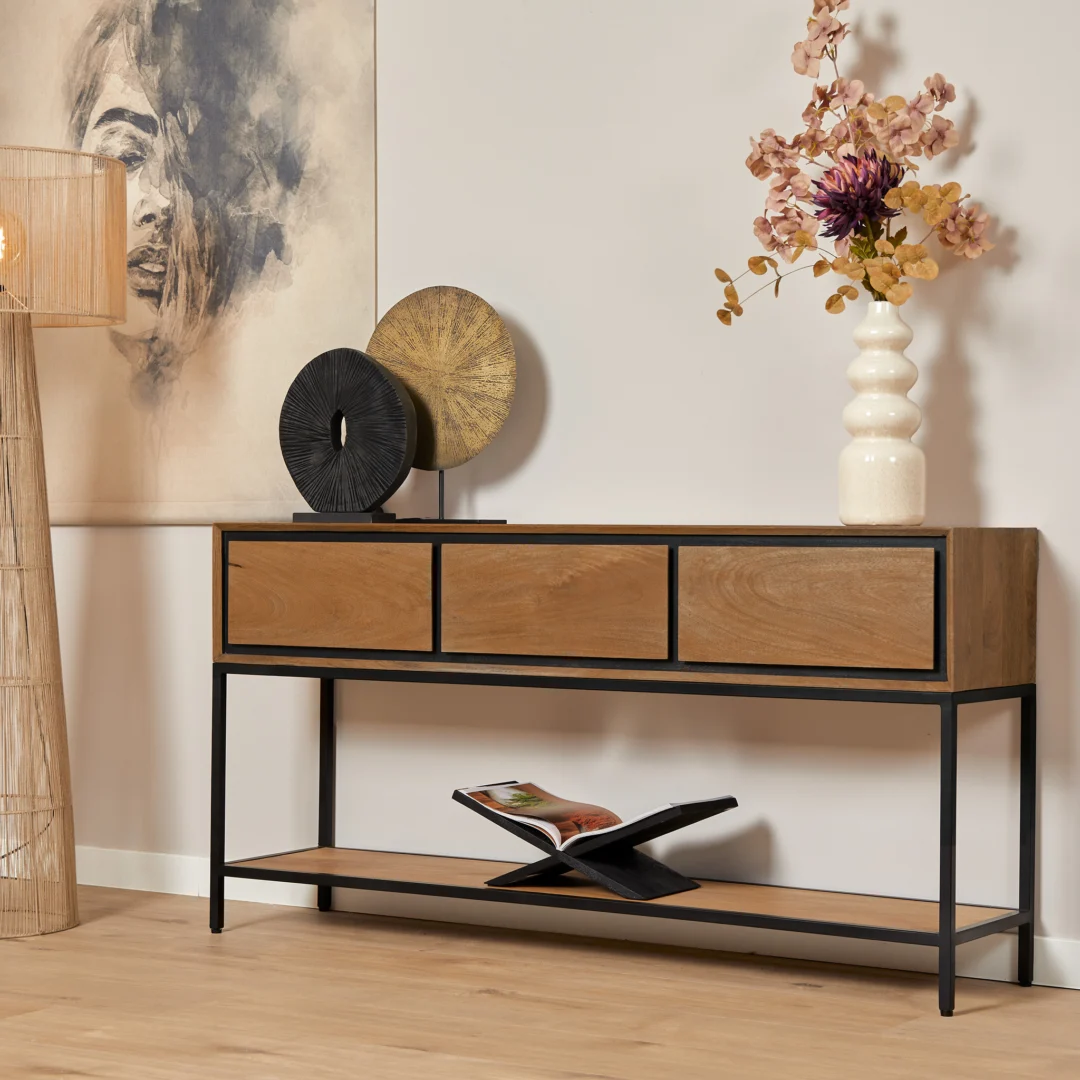 Houten sidetable met strak, zwart metalen frame en drie lades. Decoratie: vaas met bloemen, abstracte kunst. Warme, natuurlijke kleuren.