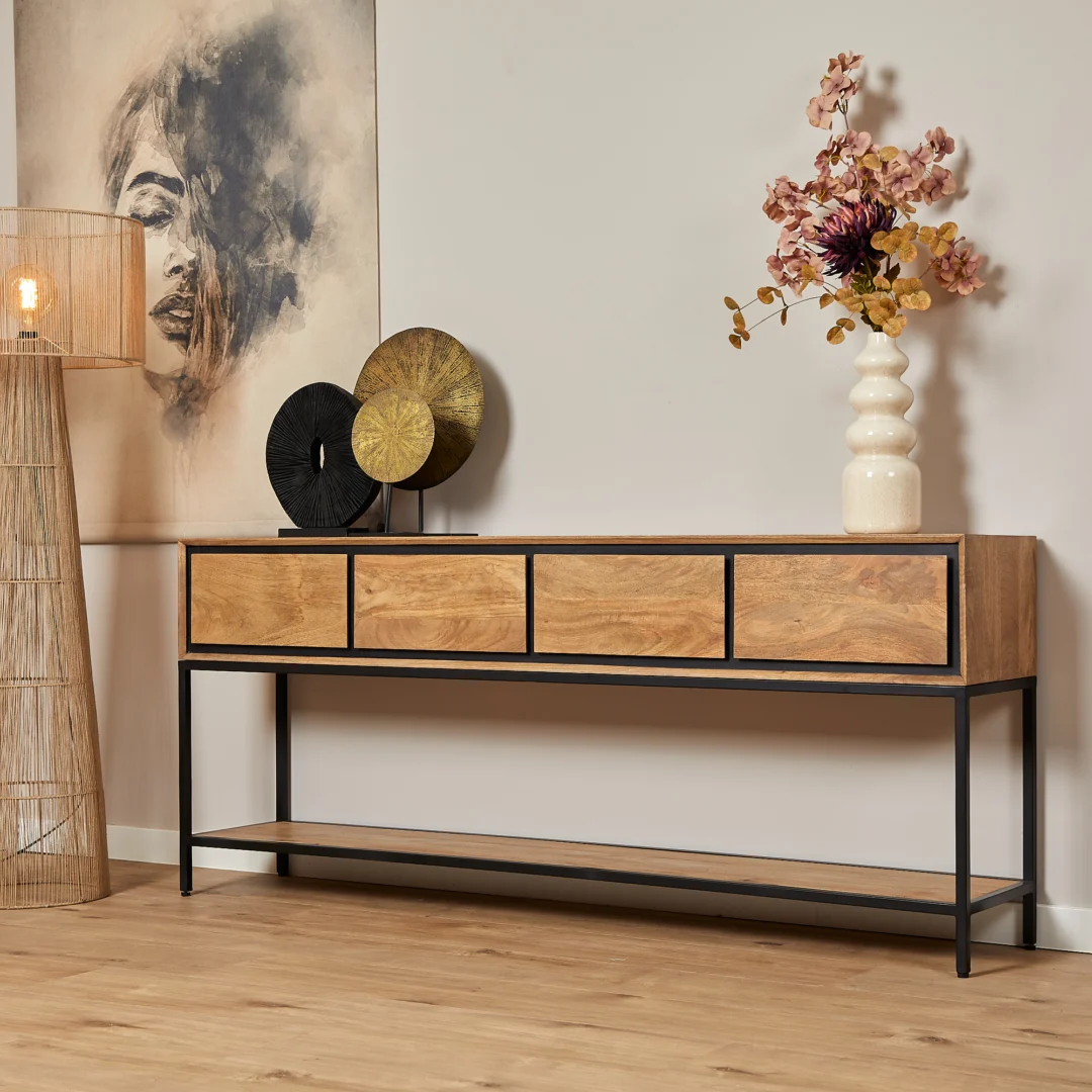 Lichte houten sidetable RichWood met zwarte metalen frame. Vier lades en een plank. Decoratieve objecten en een vaas met bloemen erop. Warme verlichting.