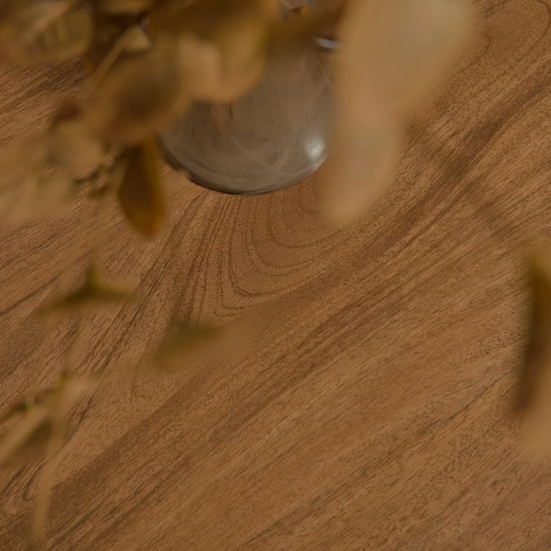 Houten salontafelblad in close-up, warme tinten. Een vaas en gedroogde bloemen staan erop. Het hout heeft een duidelijke, natuurlijke nerf.