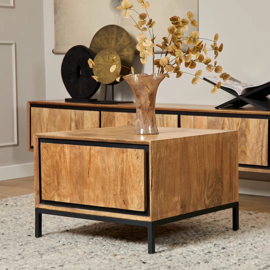 De Bijzettafel RichWood | 60 cm, een vierkante houten bijzettafel met zwart metalen poten, bevat een glazen vaas met gouden decoratieve takken. Op de achtergrond staat een bijpassende houten consoletafel met decor.