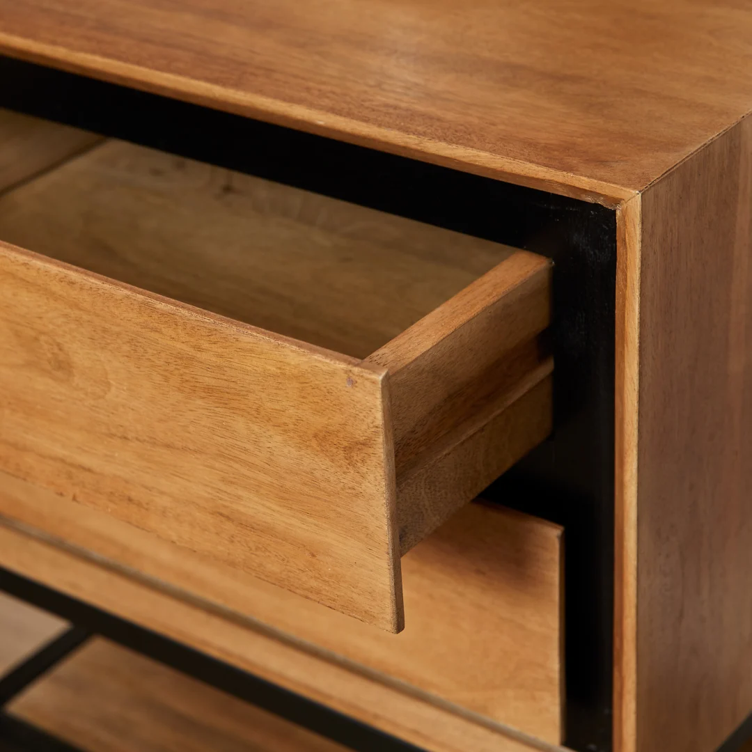 Detailopname van een houten nachtkastje met lade, open. Warme houttinten contrasteren met zwarte accenten. Zachte belichting, scherpe focus.