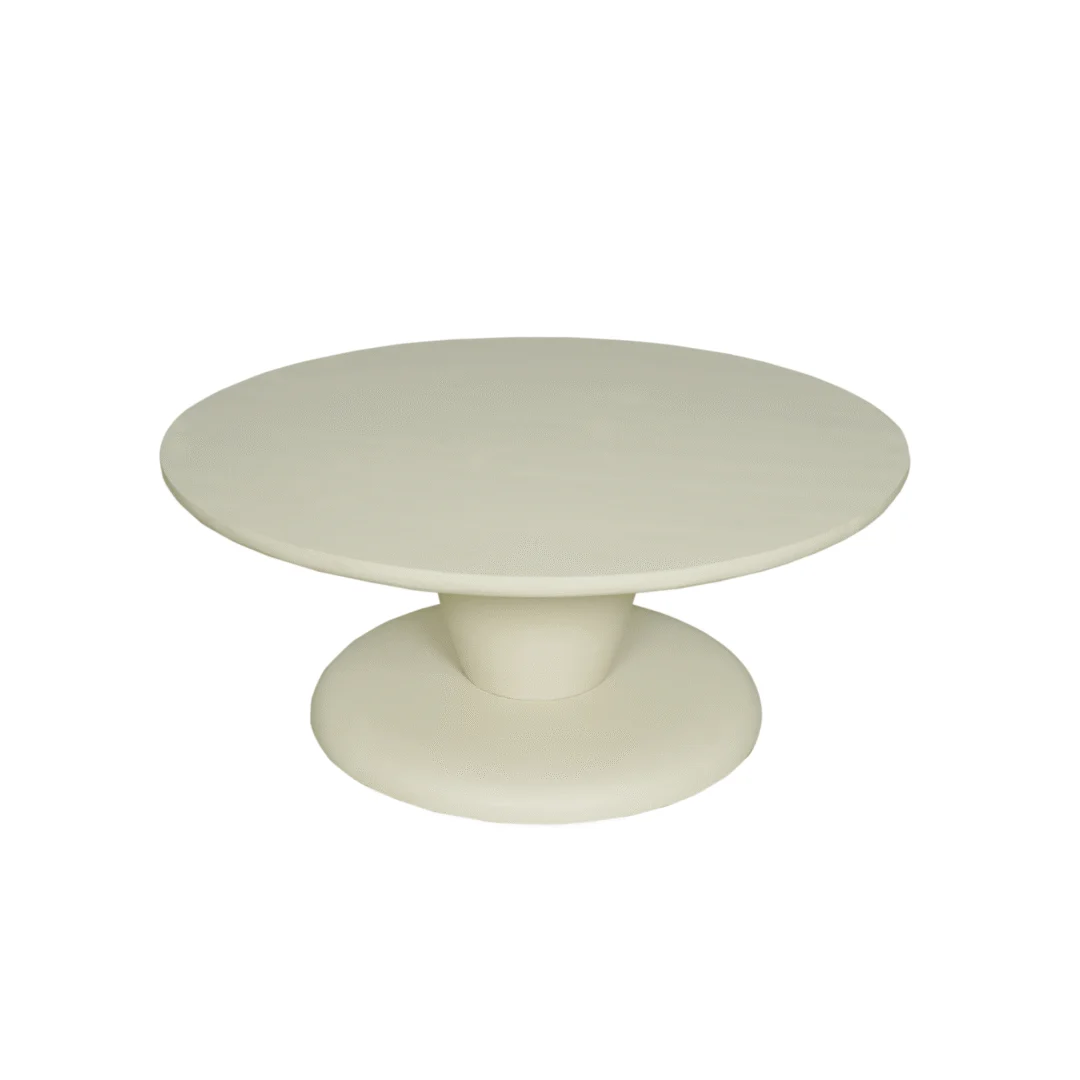 Zijaanzicht van een ronde, crèmekleurige salontafel met een voetstuk op een witte achtergrond. Zachte belichting accentueert de gladde afwerking.