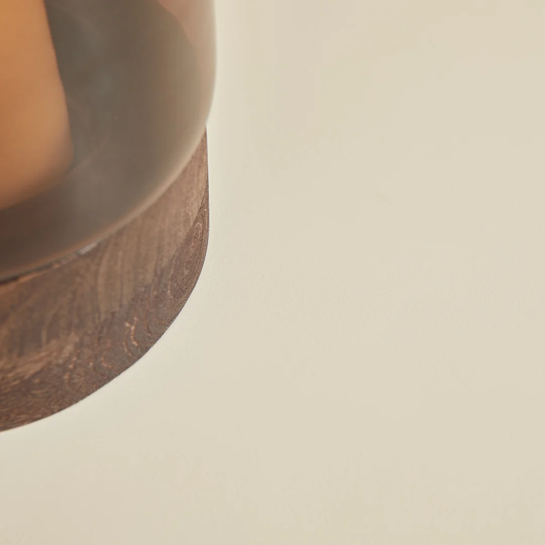 Detailopname van een houten salontafel. De tafel heeft een donkere afwerking en staat op een crèmekleurige achtergrond. Het hout heeft een zichtbare nerf.