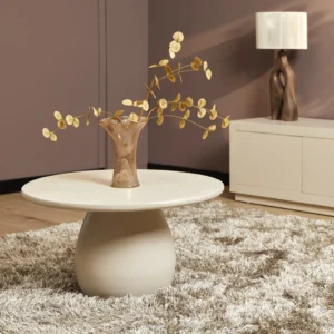 In een moderne woonkamer staat de Salontafel 70 CM Vierkant op een pluche shag tapijt, met daarop een taupe vaas met gedroogde gouden takken. Een lamp en kast staan tegen een mauve muur op de achtergrond.