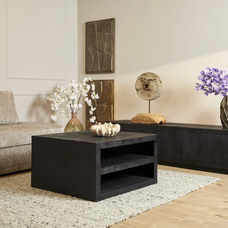 Een moderne woonkamer met Salontafel Zwart Design Tijdloos Design, een beige bank, neutrale inrichting, vazen met witte en paarse bloemen, abstracte muurkunst, een dressoir met structuur en een licht geweven vloerkleed.