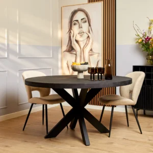 Een moderne eethoek met de Eettafel Denver Zwart ronde tafel (110 cm), twee beige stoelen, decoratieve vazen, een fruitschaal, een bloemenvaas en een groot vrouwenportret aan de muur op de achtergrond.