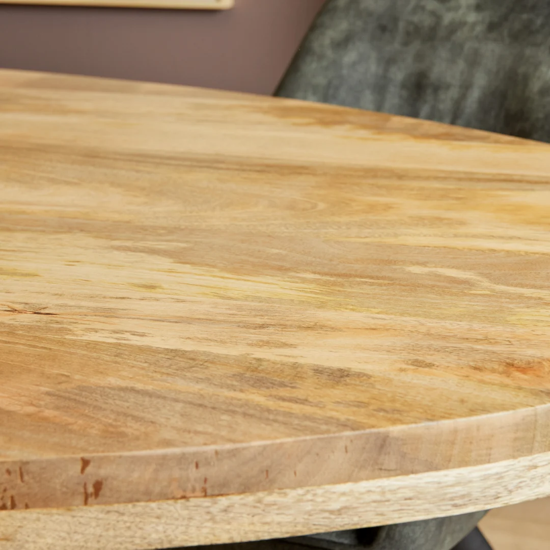Een close-up van de Eettafel Denver, een ovale eettafel van 210 cm gemaakt van licht mangohout met zichtbare natuurlijke nerven, getoond naast een donker gestoffeerde stoel.