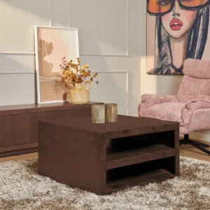 Een moderne woonkamer met de Salontafel Walnoot Compact op een shaggy licht vloerkleed, muurkunst, een roze fauteuil met structuur en een dressoir versierd met decoratieve items zoals een vaas met gedroogde bloemen.