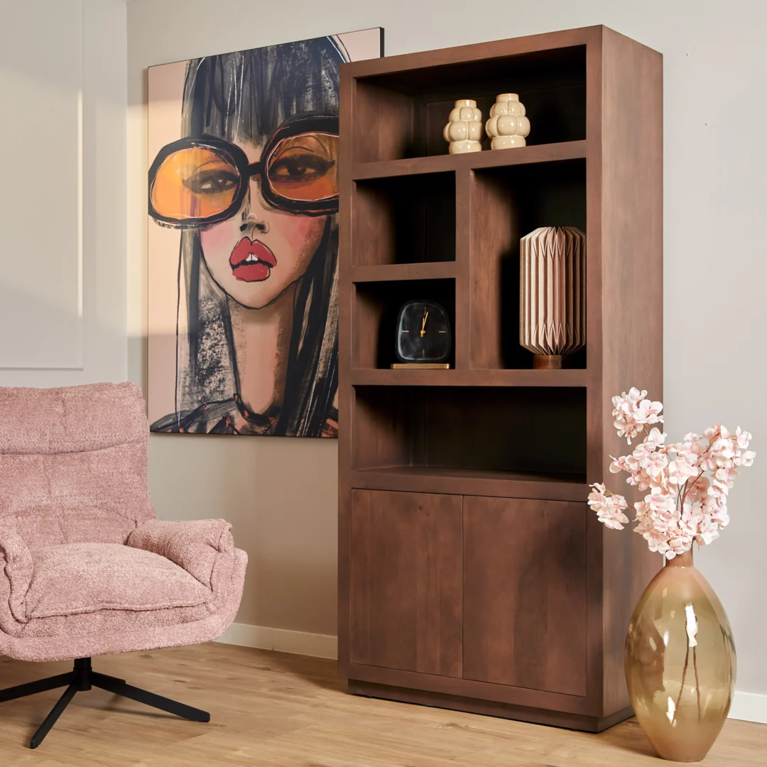 Een gezellige kamer heeft een roze fauteuil met structuur, een moderne bruine Salontafel Walnoot Compact, decoratieve vazen, een groot schilderij van een vrouw met een te grote zonnebril en een hoge vaas met roze bloemen op de vloer.