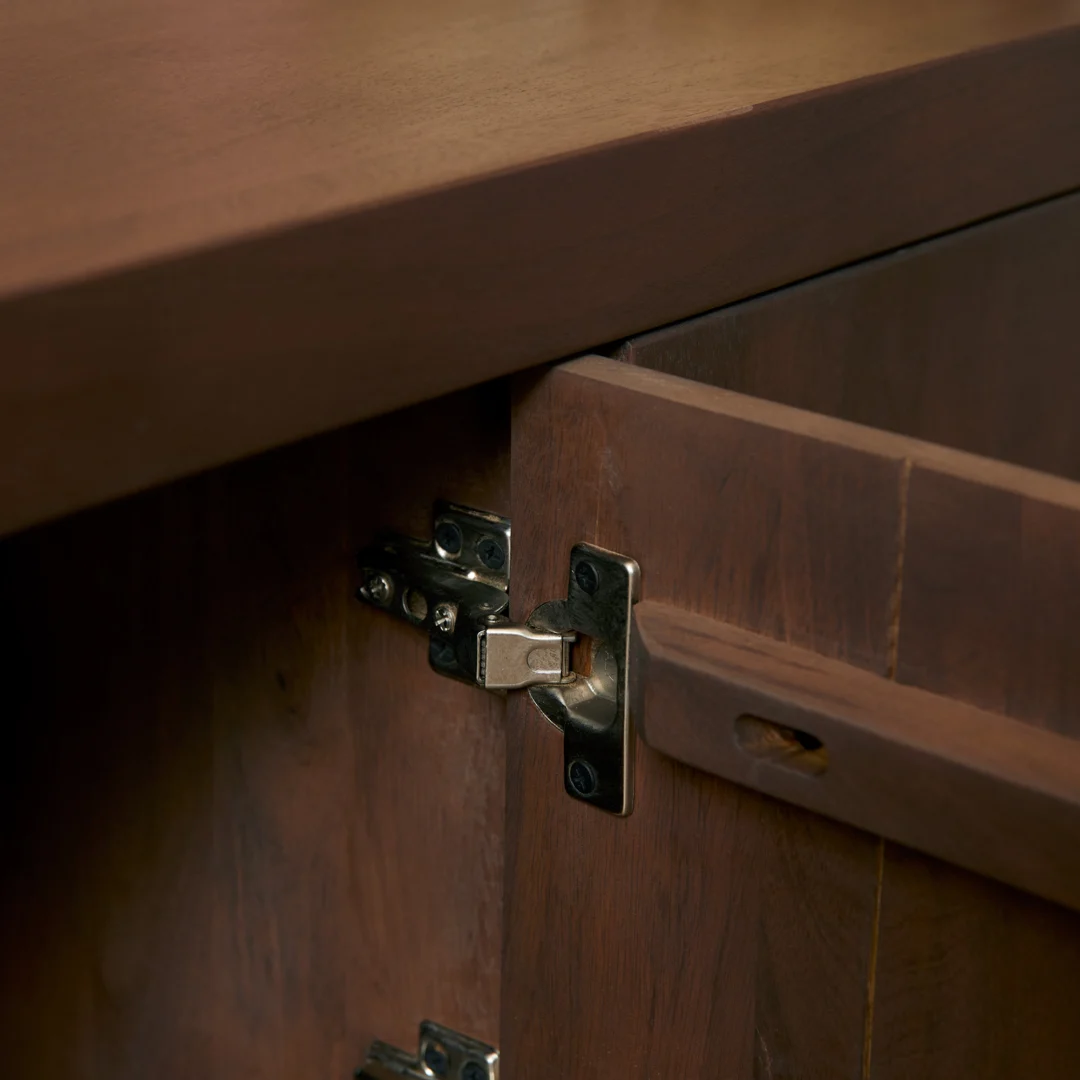 Een close-up van de Salontafel Walnoot Compact toont het houten oppervlak met de deur iets open, waardoor een stevig metalen scharnier zichtbaar wordt dat de deur met het frame verbindt.