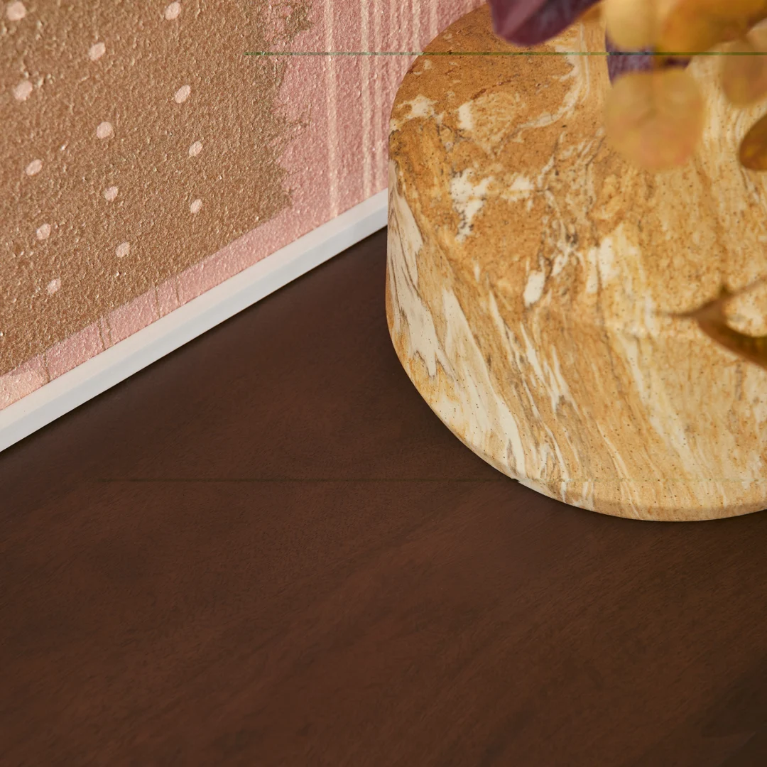 Een close-up van een marmeren vaas met gele en witte patronen op een Salontafel Walnoot Compact, naast een ingelijst abstract kunstwerk met roze en beige tinten.