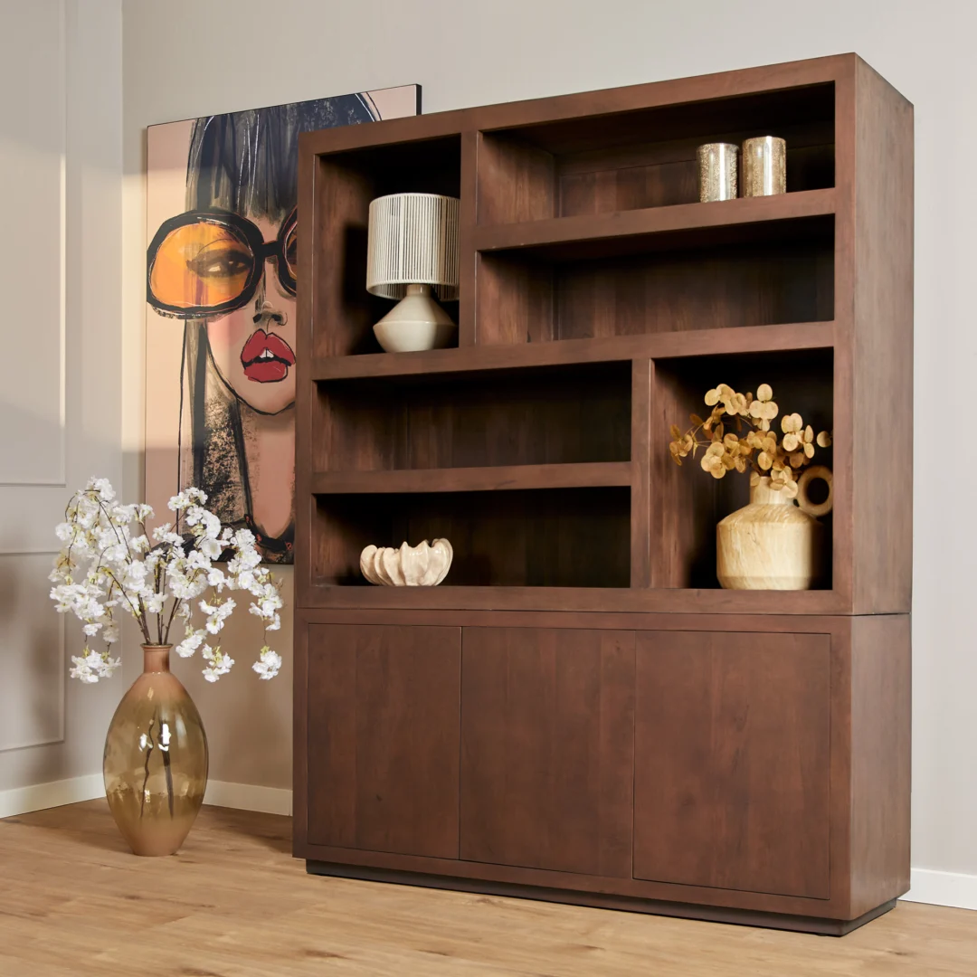De Salontafel Walnoot Compact staat naast een grote vaas met witte bloemen en een stijlvol schilderij van een vrouw met een te grote bril, terwijl op houten planken vazen, boeken en een lamp staan voor een moderne inrichting.