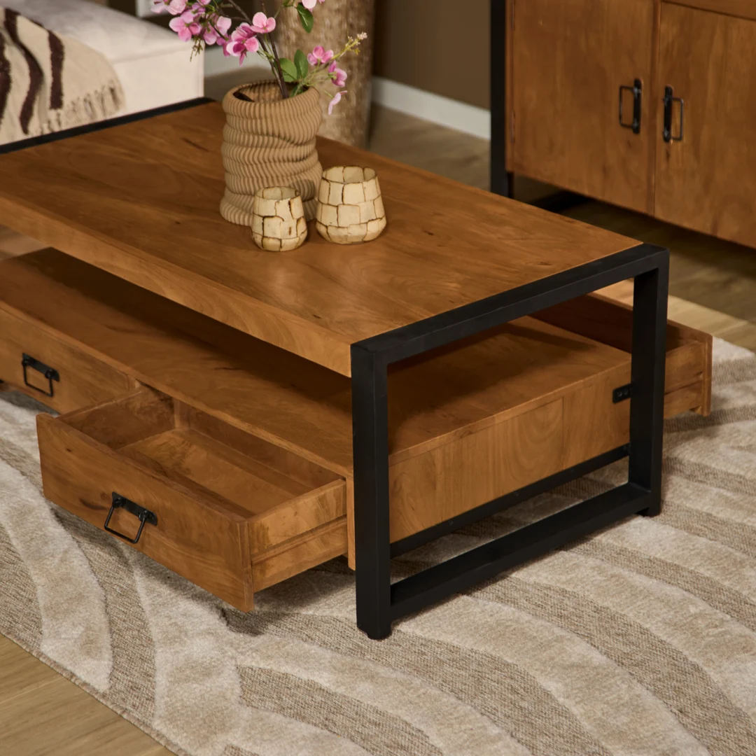 De Salontafel 120 x 60 CM Klassiek, een houten salontafel met zwart metalen poten en twee open lades, is afgewerkt met een vaas roze bloemen en twee decorstukken. Hij staat op een tapijt met een beige patroon in een moderne woonkamer.