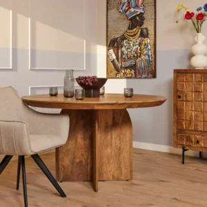 De Eettafel Tense | 150 cm | Rond staat met glaswerk en druiven naast een beige stoel. Op de achtergrond versterken een dressoir, bloemenvaas en kleurrijke portretkunstwerken de zonovergoten, gezellige sfeer van de kamer.