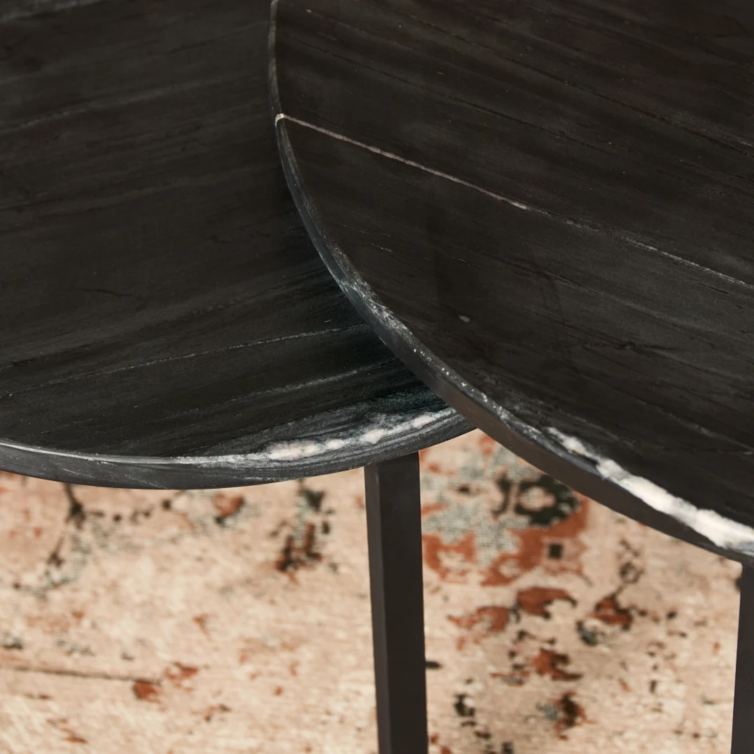 Twee ronde Salontafel Zwart 70 x 70 CM Rond Marmer tafels met zichtbare witte adering en dunne zwarte metalen poten overlappen elkaar op een beige en roestpatroon vloerkleed.