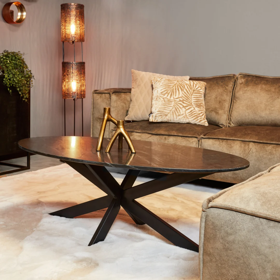 Moderne woonkamer met een beige sofa, sierkussens, een salontafel Zwart 130 CM Ovaal Marmer, een gouden decorstuk, een staande lamp met geweven kappen en een crèmekleurig vloerkleed.