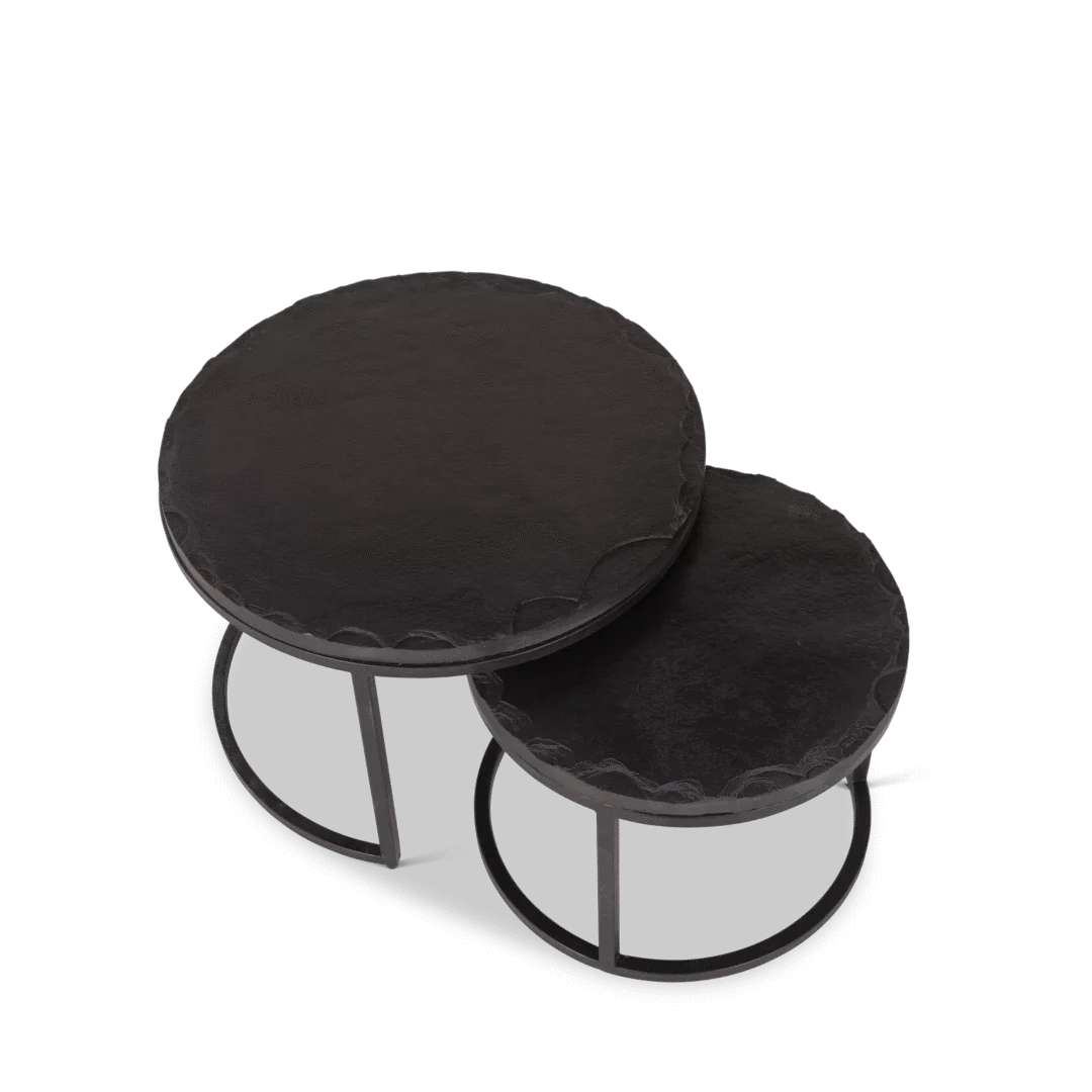 De Salontafel Zwart 61 x 61 CM Steen set bestaat uit twee ronde, zwarte nesttafels met slanke metalen frames. Elke tafel heeft een andere hoogte en afmeting, waardoor de kleinere gedeeltelijk onder de grotere tafel kan worden geschoven.