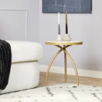 Een moderne woonkamer met een witte bank, een crèmekleurig vloerkleed met een zwart ruitpatroon en de Kay bijzettafel van wit marmer (40 cm) met twee geometrische kandelaars. Boven de lichtgrijze muur hangt een donker abstract kunstwerk.