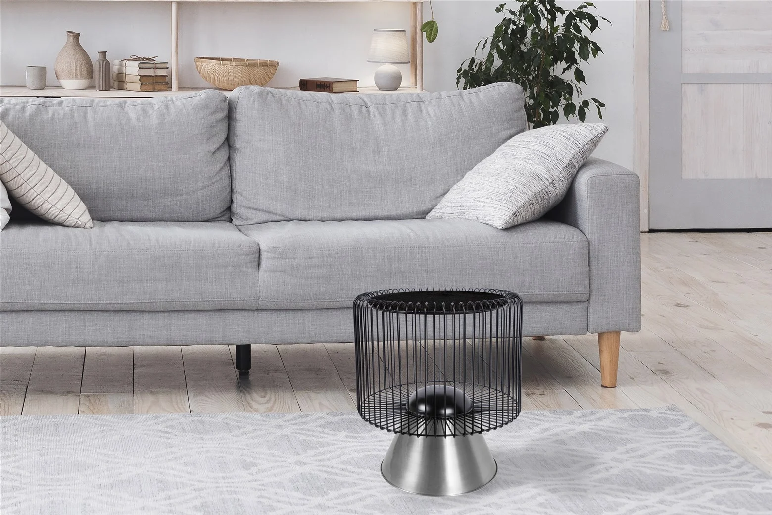 Een moderne woonkamer is voorzien van een lichtgrijze bank, een grijs gedessineerd vloerkleed en de Bijzettafel Zilver, Zwart 40 CM Rond - een unieke zwart metalen en zilver marmeren bijzettafel - samen met decoratieve planken, een potplant en neutrale accenten voor een gezellige minimalistische sfeer.