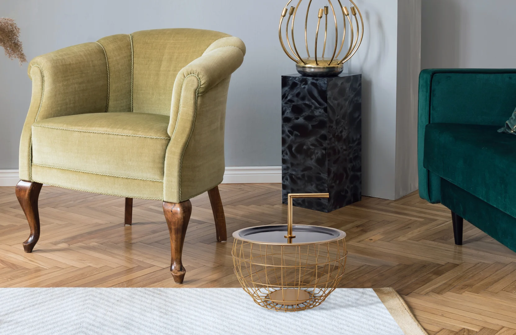 Een lichtgroene vintage fauteuil staat op een visgraat houten vloer naast een groene bank. Aan de voorkant staat de Bijzettafel Zwart 13 CM Rond Ijzer Design, vormgegeven als een modern zwart ijzeren bijzettafeltje.