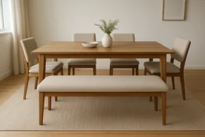 Een minimalistische eetkamer met een houten tafel, vier beige gestoffeerde stoelen, een bijpassende bank en een licht vloerkleed; net als het verschil tussen een salontafel en een bijzettafel brengt elk stuk een unieke functie en stijl met zich mee terwijl het licht naar binnen stroomt vanuit een nabijgelegen raam.