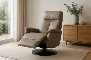 Een moderne bruine leren fauteuil met verlengde voetsteun staat op een beige vloerkleed naast een licht houten dressoir met vazen en een groene plant - perfect om te ontspannen of na te denken over wat het verschil is tussen een salontafel en een bijzettafel. Zonlicht valt door de transparante gordijnen.