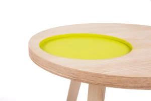 Een close-up van de Bijzettafel Groen Rond Mdf, een minimalistische ronde tafel met lichthouten poten en een verzonken rond blad met een helder geelgroen oppervlak.