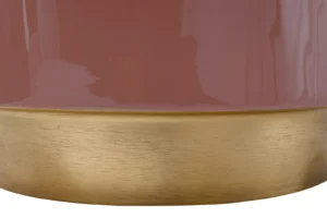 Close-up van de Bijzettafel Metaal Rond, een glanzend mauve cilindrische tafel met een geborsteld goud metallic onderstel. Het reflecterende oppervlak vangt licht en vormen dichtbij, waardoor subtiele highlights en schaduwen ontstaan.