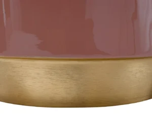 Close-up van de Bijzettafel Metaal Rond, een glanzend mauve cilindrische tafel met een geborsteld goud metallic onderstel. Het reflecterende oppervlak vangt licht en vormen dichtbij, waardoor subtiele highlights en schaduwen ontstaan.