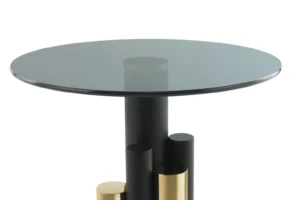 De Bijzettafel Grijs, Goud Aluminium is een moderne bijzettafel met een rond glazen blad en een opvallend onderstel van zwart en goud aluminium cilindervormige steunen in verschillende hoogtes.