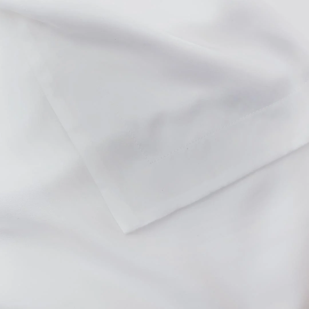 Een close-up van het Dekbedovertrek Wit 200x200 toont netjes gevouwen witte stof met een zachte, gladde textuur, scherpe randen en strakke lijnen. Het dekbedovertrek is vochtregulerend voor extra comfort.