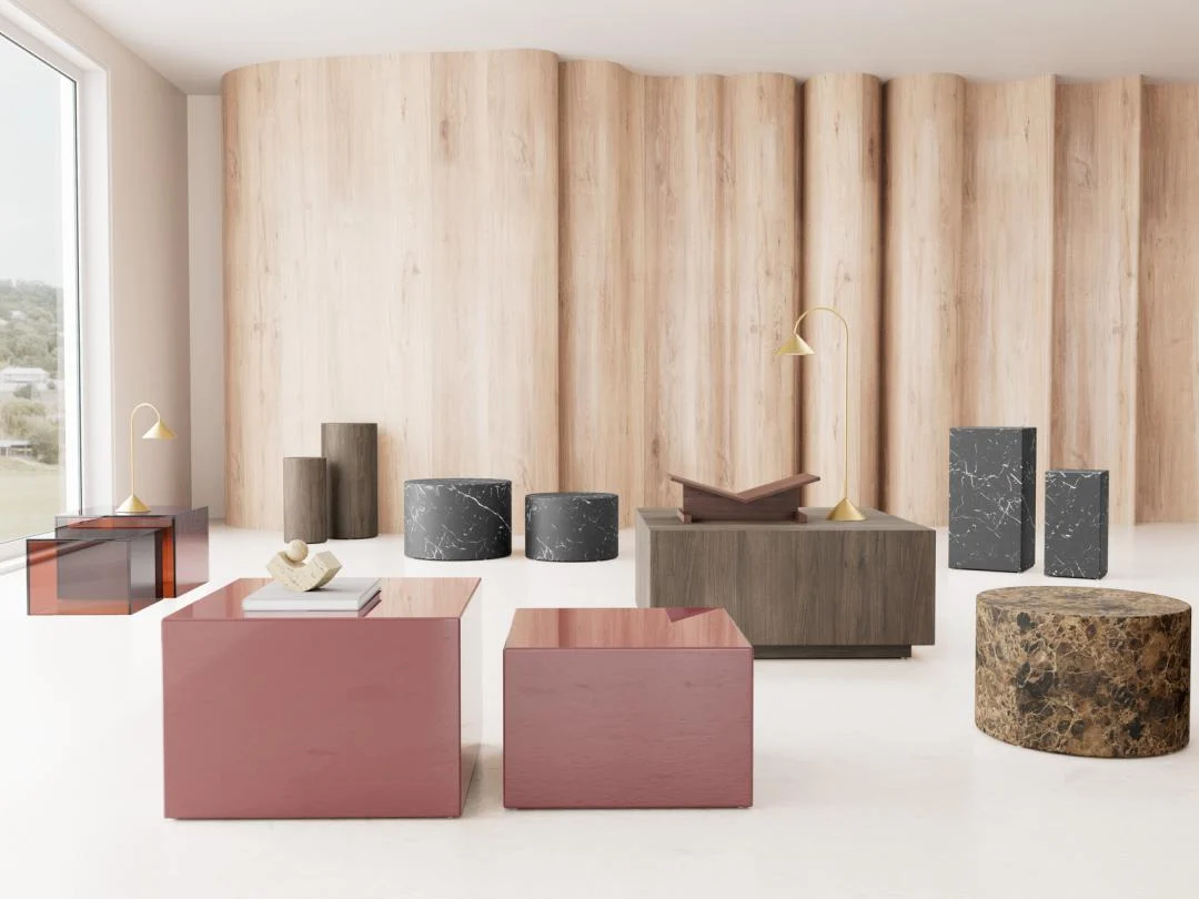 Interieur met bruine en roze salontafels van kunststof, cilindervormige bijzettafels van marmer, houten achtergrond en natuurlijk licht.