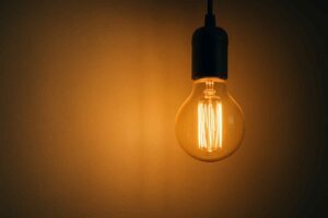 Gloeilamp met warm licht tegen een bruine achtergrond. De lamp is helder en de achtergrond is donkerder. Design element voor een zitbank.