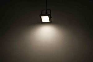 Een vierkante spot verlicht een donkere muur. Het licht is helder en wit. Het design is modern en minimalistisch. Comfortabele verlichting.