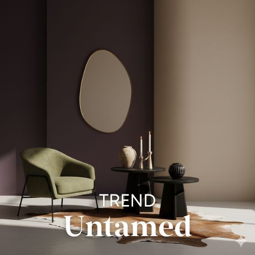Interieur met olijfgroene stoel, zwarte tafels en een spiegel tegen een paarse wand. Een huidkleurig vloerkleed maakt de woontrend compleet.