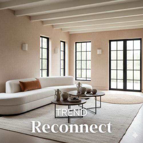 Lichte woonkamer met witte balken, crèmekleurige muren, en een lange witte bank. Ronde tafels met decoratieve vazen. Zwarte kozijnen. Woontrends.