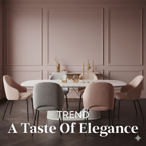 Eetkamer interieur met roze muren en een ovale tafel. De stoelen zijn bekleed met zachte stoffen in grijze en roze tinten. Woontrends.