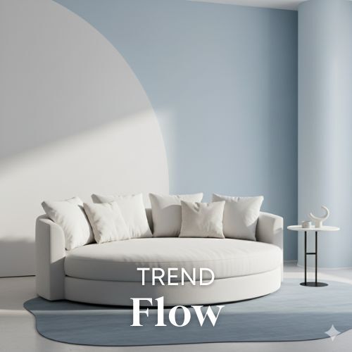 Lichte ronde bank met kussens in een kamer met blauwe accentmuur en ronde vormen. Minimalistisch interieur en zachte belichting. Woontrends.