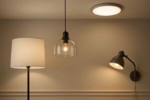 Verschillende lampen in een woonkamer: een vloerlamp met kap, een hanglamp met glas en een wandlamp. Zachte, warme verlichting.
