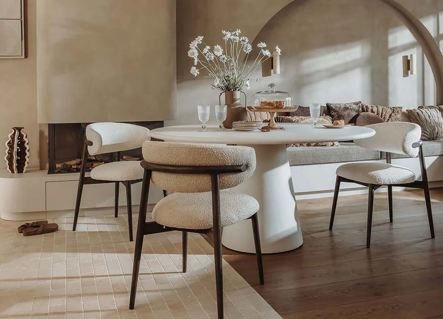 Lichte eetkamer met ronde tafel en zachte stoelen. Neutrale tinten, natuurlijk licht. Woonideeën: gezellige zithoek met open haard.