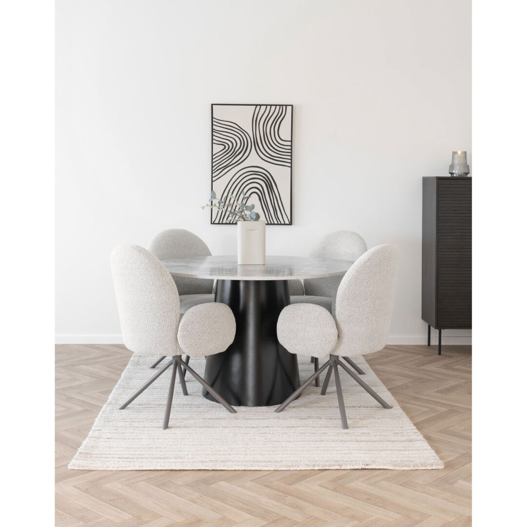 Een ronde eettafel met marmereffect, omringd door vier Lana eetkamerstoelen met een zachte, witte bekleding en metalen poten, op een licht tapijt.