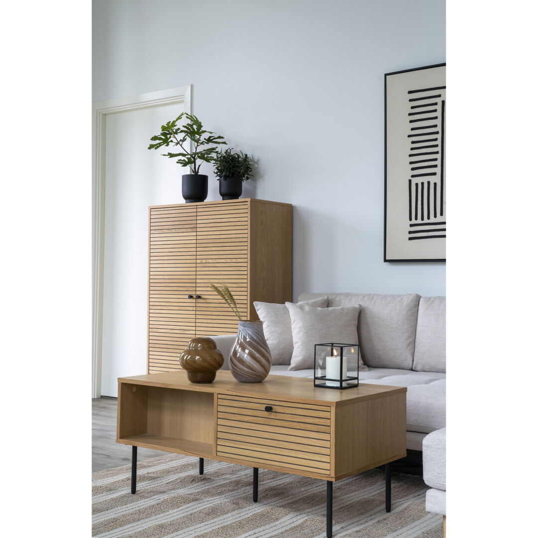 Eiken salontafel met design kast, vazen en kaars. Lichte tinten en horizontale lijnen op het hout. Zachte belichting en moderne sfeer.