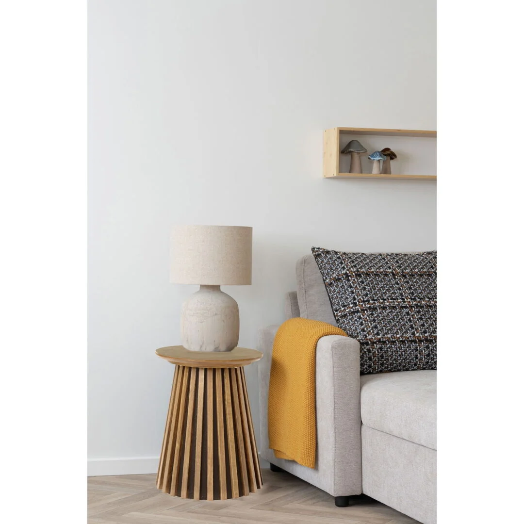 Eikenfineer bijzettafel met lamp en bank, zachte kleuren. Rustige sfeer, natuurlijk licht. Strak design, eikenhout en lichte tinten.