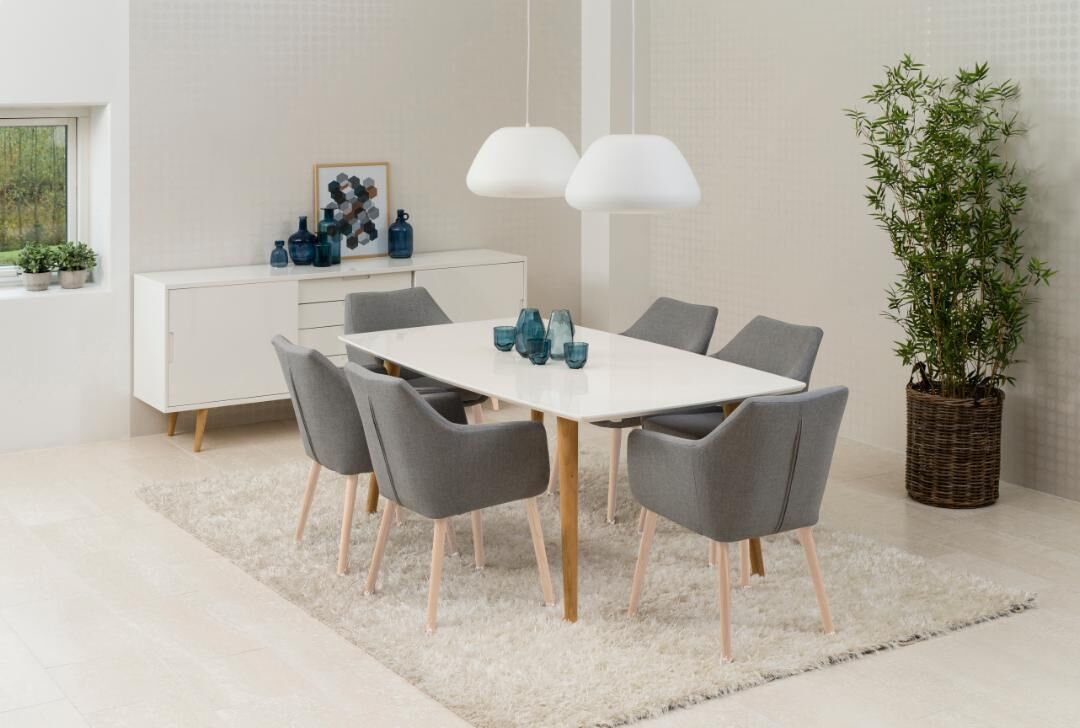 Nora eetkamerstoel met armleuning: Grijze stoelen rondom een witte eettafel met moderne hanglampen.