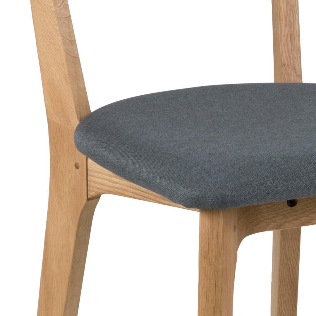 Taxi eetkamerstoel detail: grijze zitting met houten frame.