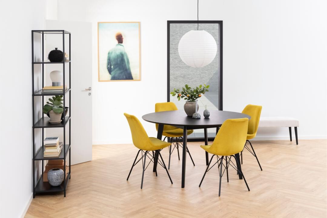 Eetkamer met zwarte tafel, vier gele Eris eetkamerstoelen (set van 2), en zwarte stellingkast.
