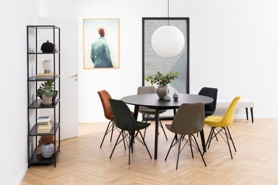 Moderne eetkamer met ronde zwarte tafel en Eris eetkamerstoelen in diverse kleuren.