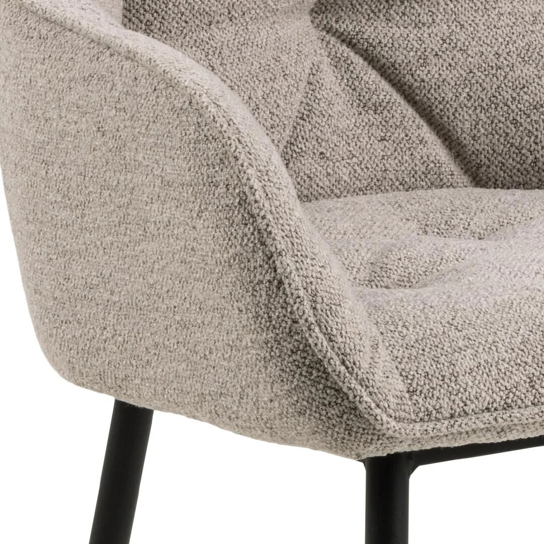 Brooke eetkamerstoel met armleuning: detailopname van de beige stoffering en zwarte poten.